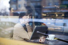 Woman watches national-local ad on tablet in coffee house